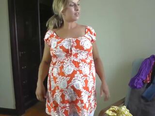 Captivating pregnant sweetheart trying on dresses